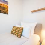 Schlafzimmer mit Bett, Kissen und Wandbild.