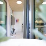 Durchgehendes Wohn- und Essbereich mit Glaswand und moderner Einrichtung.