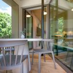 Terrasse mit Tisch und Stühlen, Blick ins Innere mit Küche und Wohnbereich.