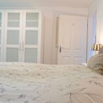 Schlafzimmer mit Bett, zwei Nachttischen und Lampen unter schräger Decke.