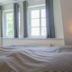 Treppenhaus mit weißer Holztreppe und Geländer. Licht fällt durch Fenster.