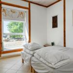 Bedroom with double bed, window, and artworks on the walls.