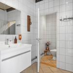 Bathroom with sink, mirror, and toilet in the adjoining room.