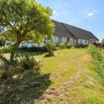 House with roof and garden, red tractor parked beside it.