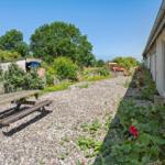 Garden with picnic table, flower beds, and gravel path beside house wall.