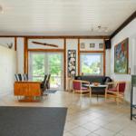 Large living and dining area with wooden ceiling, windows, and modern furniture.
