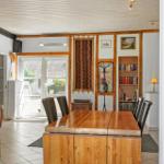 Dining room with wooden table, chairs, and bookcase. Passage to terrace with garden view.