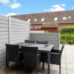 Terrasse mit Tisch und Stühlen, umgeben von grauen Sichtschutzwänden und grüner Vegetation.