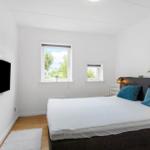 Schlafzimmer mit Bett, Fernseher und Fenstern.