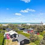 Schwarze und rote Häuser mit Flagge, Strand und Meer im Hintergrund.