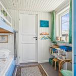 Ein Schlafzimmer mit einem Doppelstockbett, einem Schreibtisch und einem Fenster mit grünen Vorhängen.