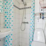 Badezimmer mit Dusche, Toilette und Waschbecken. Duschvorhang mit blauen Punkten.