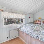 Bedroom with bed, window, and heater. Wooden floor and white walls.