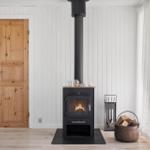 Wood stove with firewood, wooden door, and window with curtain.