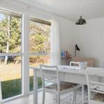 Dining room with white table and chairs. Large windows show a garden.