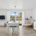 Living and dining area with table, chairs, TV, and view of garden.