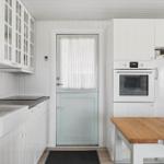 Kitchen with white cabinets, wooden table, and door with grid window.