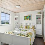 Schlafzimmer mit Bett, Fenster und weißen Schränken.