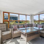 Terrassenbereich mit Sitzgruppe und Glas-Tisch. Große Fenster bieten Blick auf Garten.