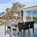 Terrasse mit Tisch und Stühlen, Blick auf Haus und Bäume.
