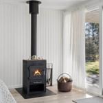 Wood-burning stove with fire, firewood, and tools in living area with wooden floor and window.