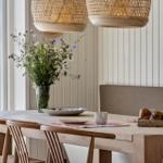Dining table with chairs, flowers, and bread basket by window with garden view.