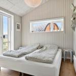 Bedroom with bed, window, and door. Outdoor view with green area and wooden house.