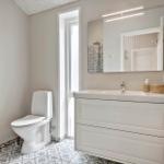 Bathroom with toilet, sink and mirror. Tile floor and heater on the wall.