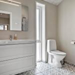 Bathroom with sink, toilet, and heater. Tile floor and mirror with light.