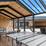 Outdoor area with ping pong table, seating, and wooden veranda under roof.