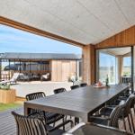 Large covered terrace with table and chairs. View of patio and garden.