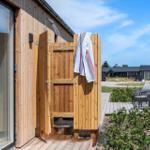 Outdoor wooden shower with towel, next to terrace and garden