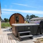 Outdoor area with hot tub and wooden sauna. Wooden deck and view of green landscape.