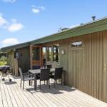 Deck with table, chairs, and grill. Wooden house with windows and door.