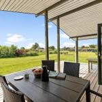 Patio with table and chairs, view of green lawn and sky.