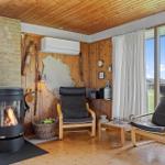 Room with fireplace, two chairs, and large window overlooking green area.