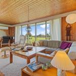 Living room with wooden ceiling, sofa, fireplace, and large window with view of the landscape.