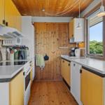 Kitchen with wooden walls, countertops, and window view of greenery.