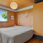 Bedroom with wooden walls, large window, and bed. Wooden ceiling, wall lamp, and wardrobe.