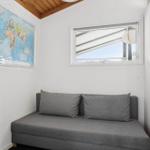 Ein Raum mit grasem Sofa, Weltkarte an der Wand und kleinem Fenster.