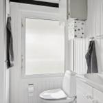 Badezimmer mit Toilette, Waschbecken und Fenster mit Milchglas.