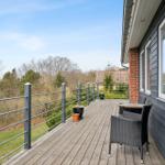 Terrasse mit Tisch und Stühlen, Blick auf Grünfläche und Nachbarhäuser.