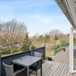 Terrasse mit Tisch und Stühlen, Blick auf Bäume und Häuser
