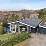 Moderne Villa mit großem Glasbereich und Garten. Blick auf Wald und Nachbarhäuser.
