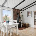 Esszimmer mit weißem Tisch, Stühlen, Kamin und Glasvitrine.
