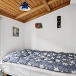 Schlafzimmer mit Bett, Fenster, Lampe und Holzdecke.
