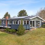 Moderne Ferienhaus mit Terrasse, Solaranlage und Garten. Holzveranda und große Fenster.