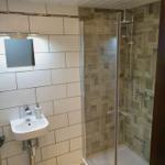 Badezimmer mit Dusche, Waschbecken und Spiegel an der Wand.