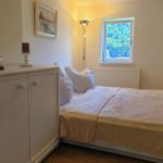 Schlafzimmer mit Bett, Schrank, Fenster und Stehlampe.