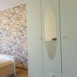 Schlafzimmer mit weißem Schrank und Steinwand